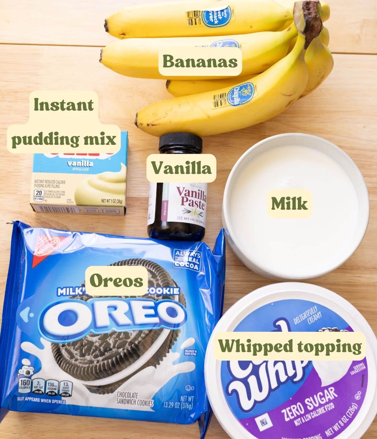 Homemade oreo banana pudding labeled ingredients on a wooden table.