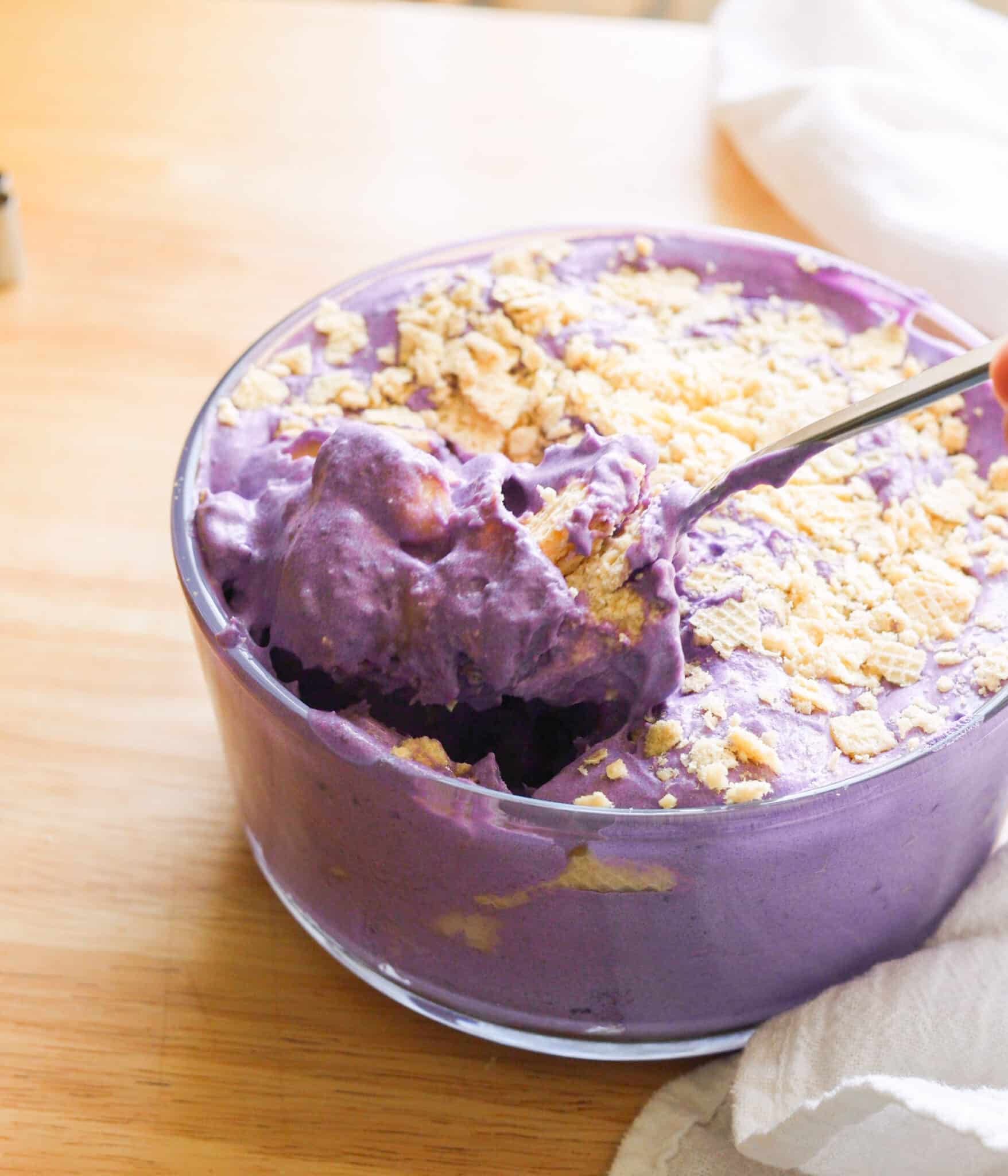 Using a spoon to eat ube banana pudding with crushed wafers on top.