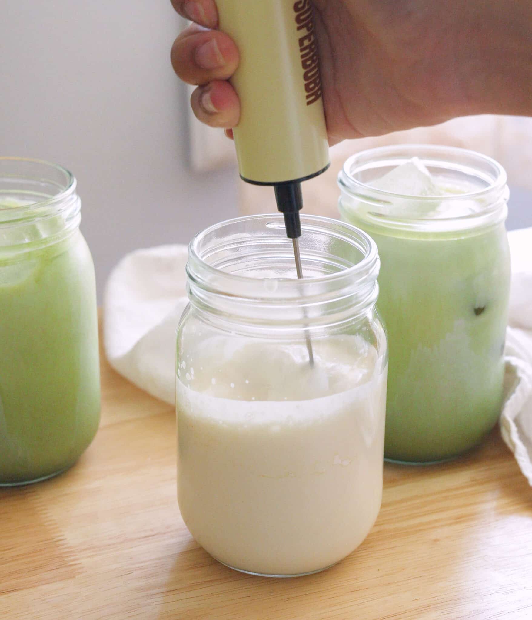 Using a mini electric whisk to mix heavy cream, milk, vanilla, and instant banana pudding mix.