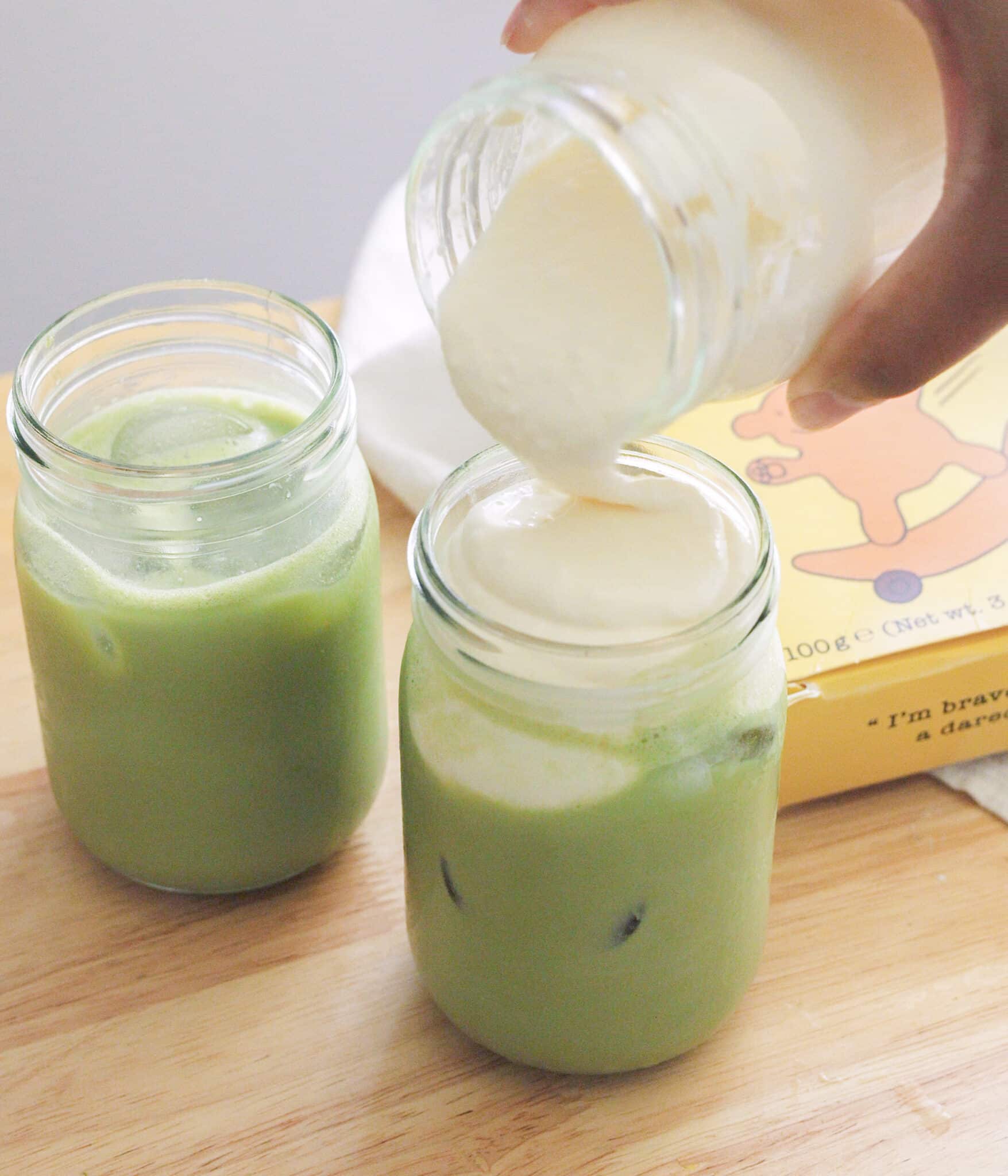 Pouring banana cream cold foam over matcha latte.
