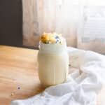 Cake shake in a mason jar topped with whipped cream and rainbow sprinkles.