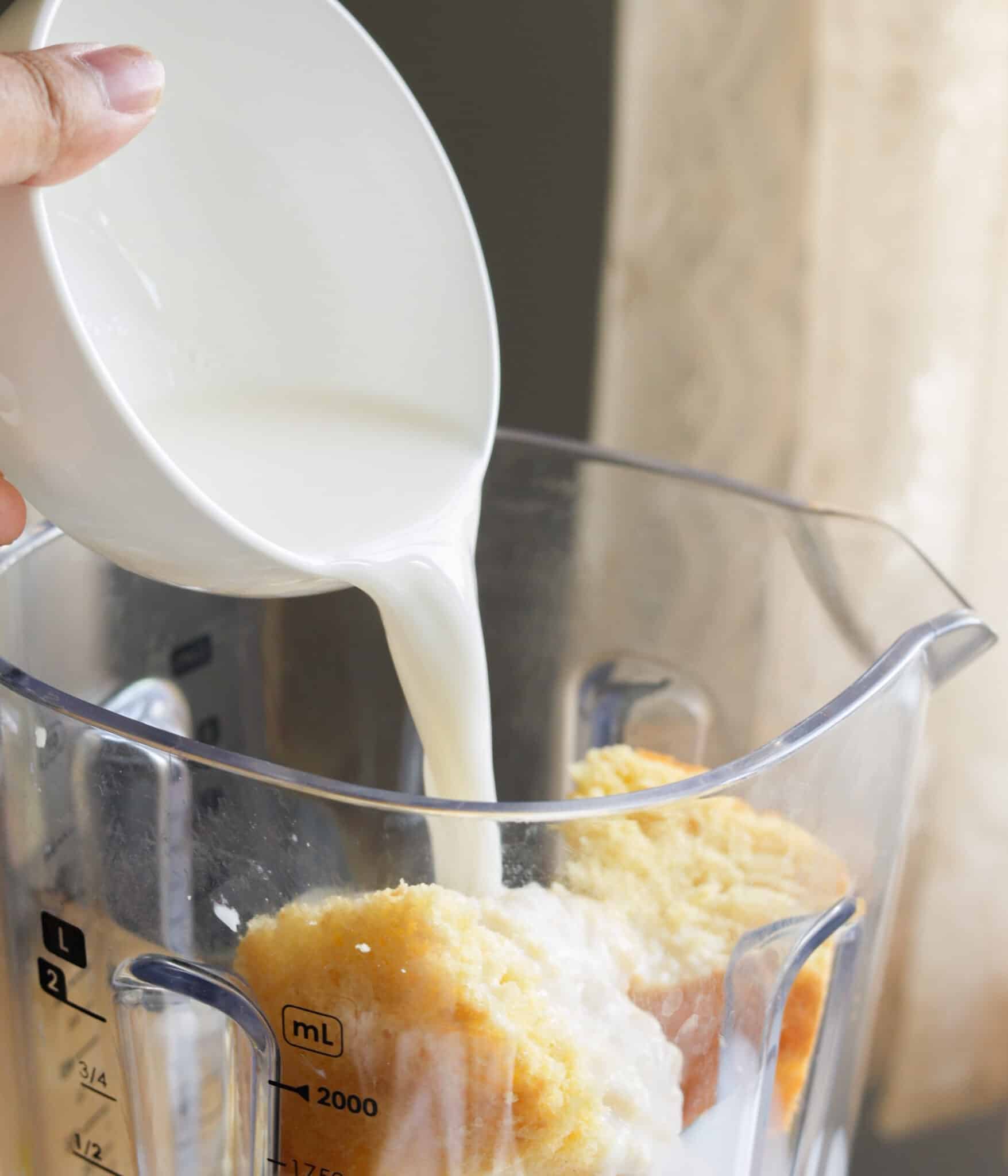 Pouring milk into blender with ice cream and yellow cake.