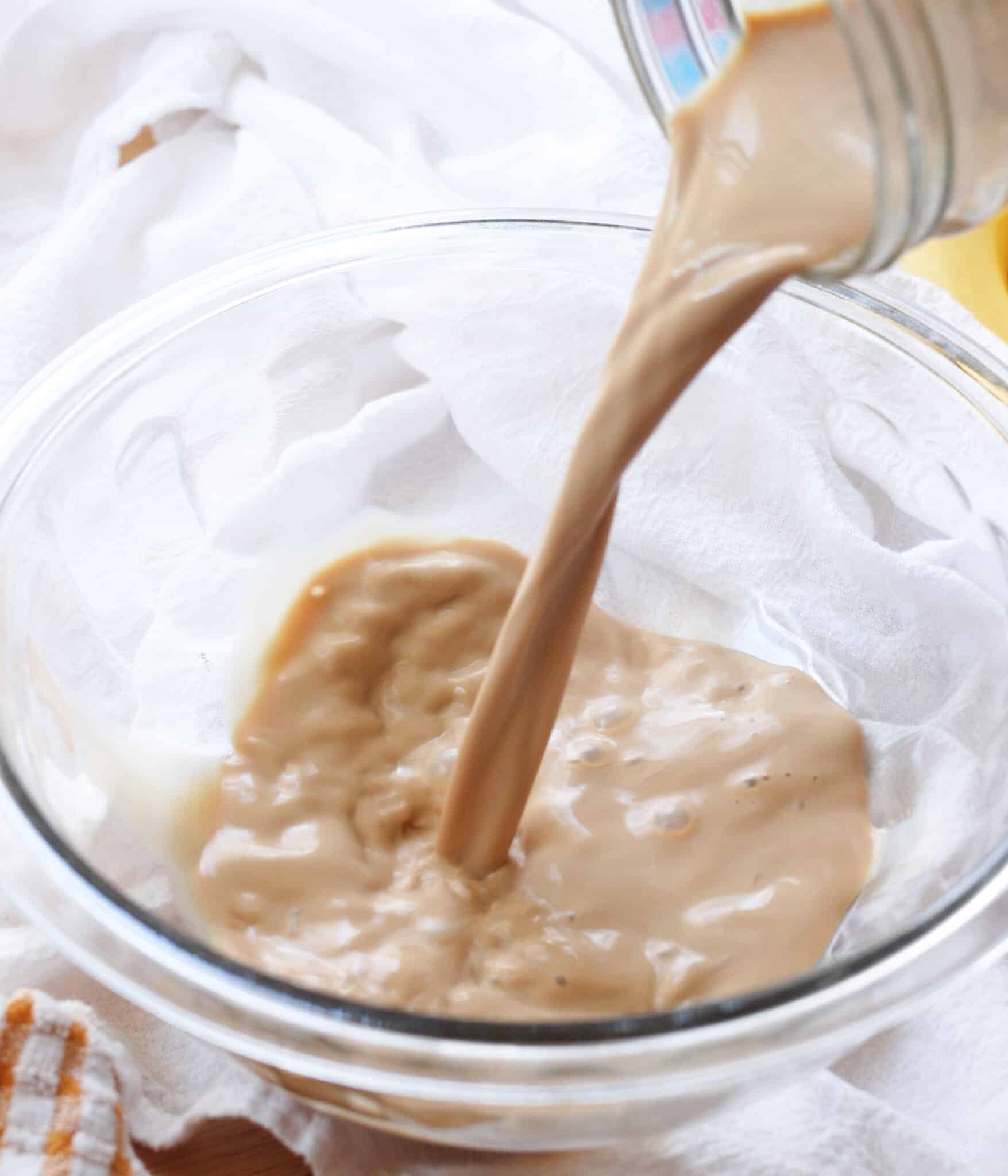 Earl grey-infused milk being poured into a glass mixing bowl.