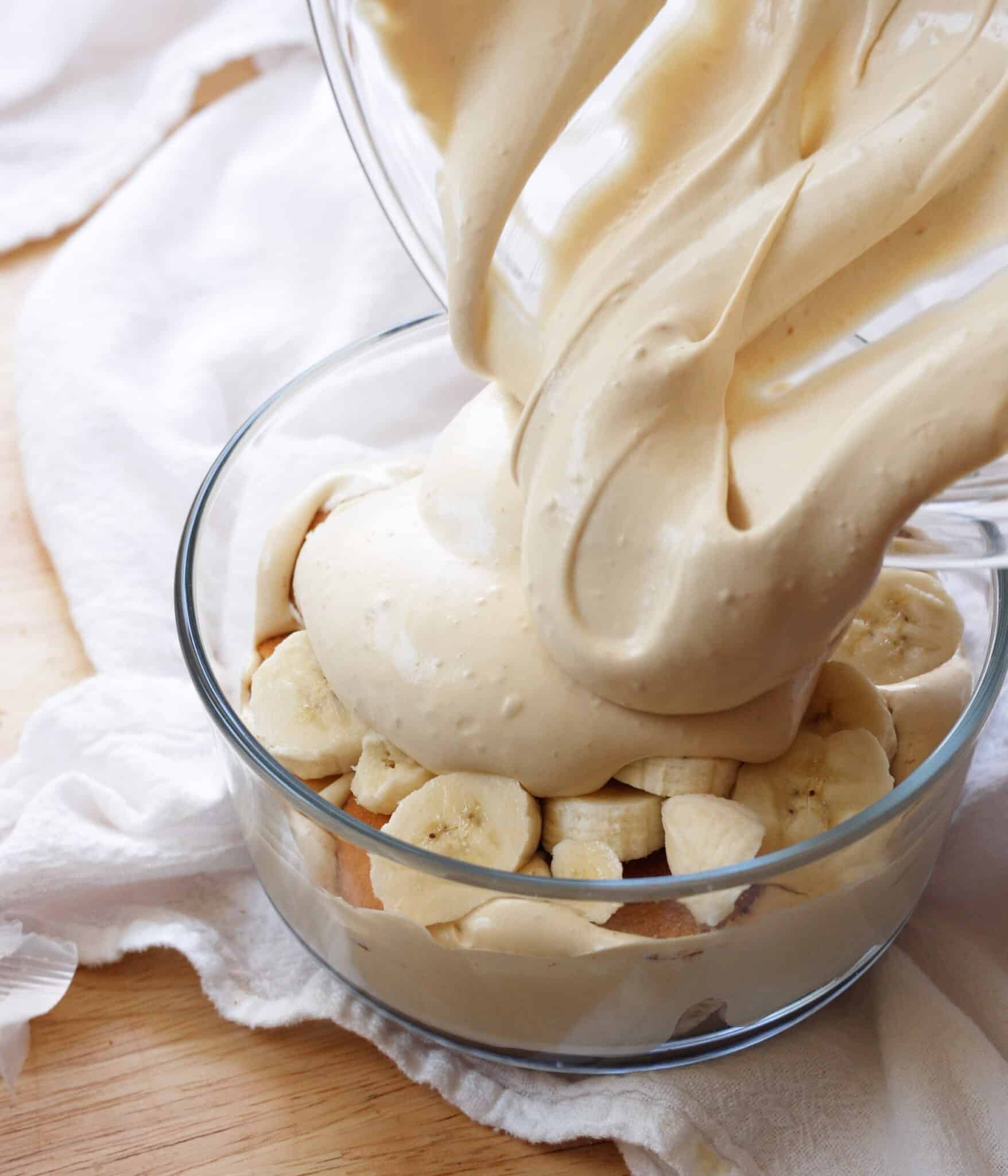 Layering earl grey pudding on top of nilla wafers and sliced bananas in a serving bowl.