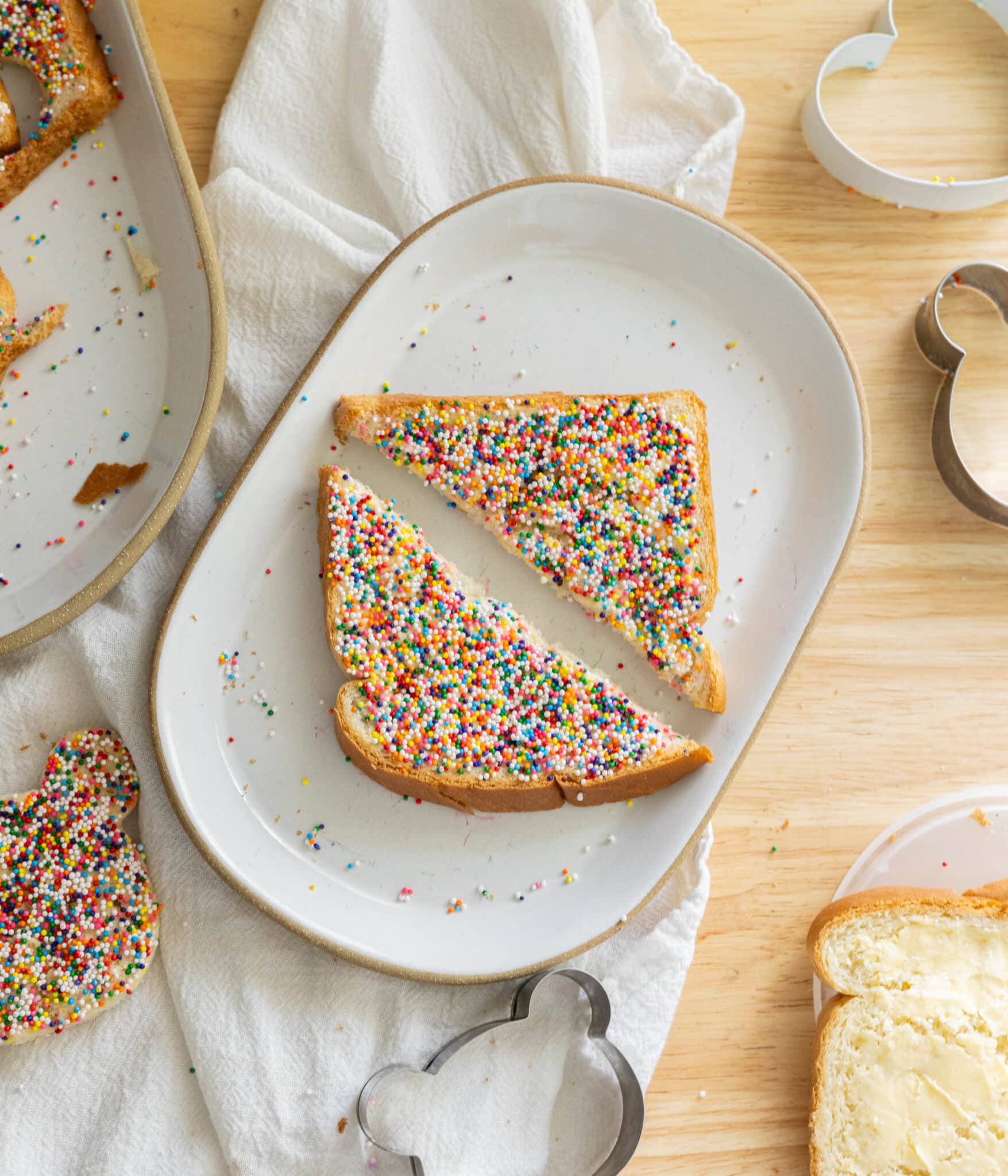Fairy bread cut into triangles on a white plate.
