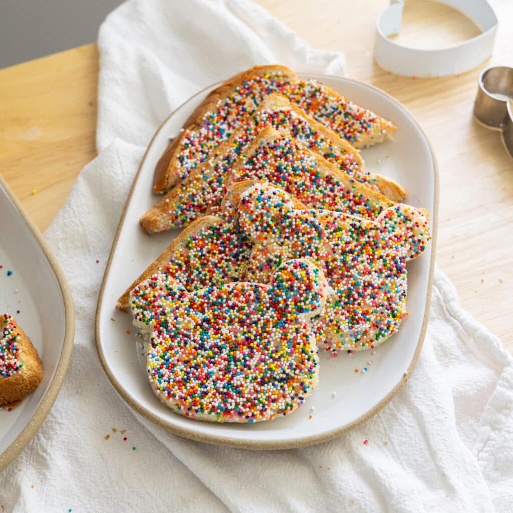 Fairy bread cut into triangles on a white plate.