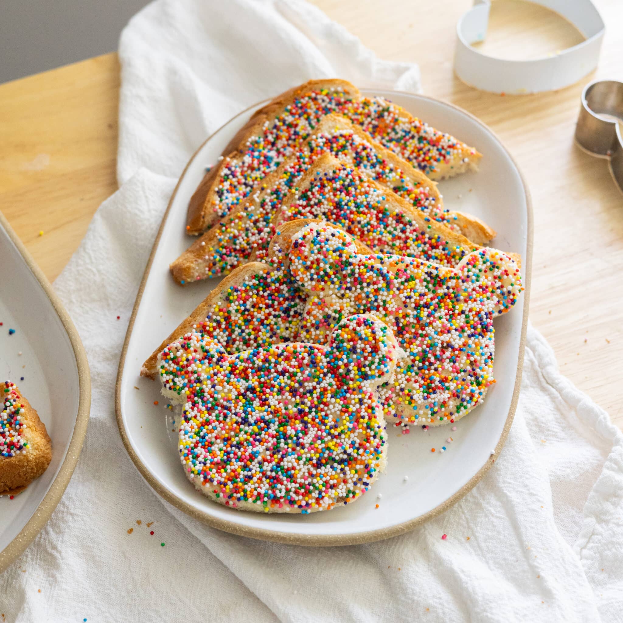 Fairy bread cut into triangles on a white plate.