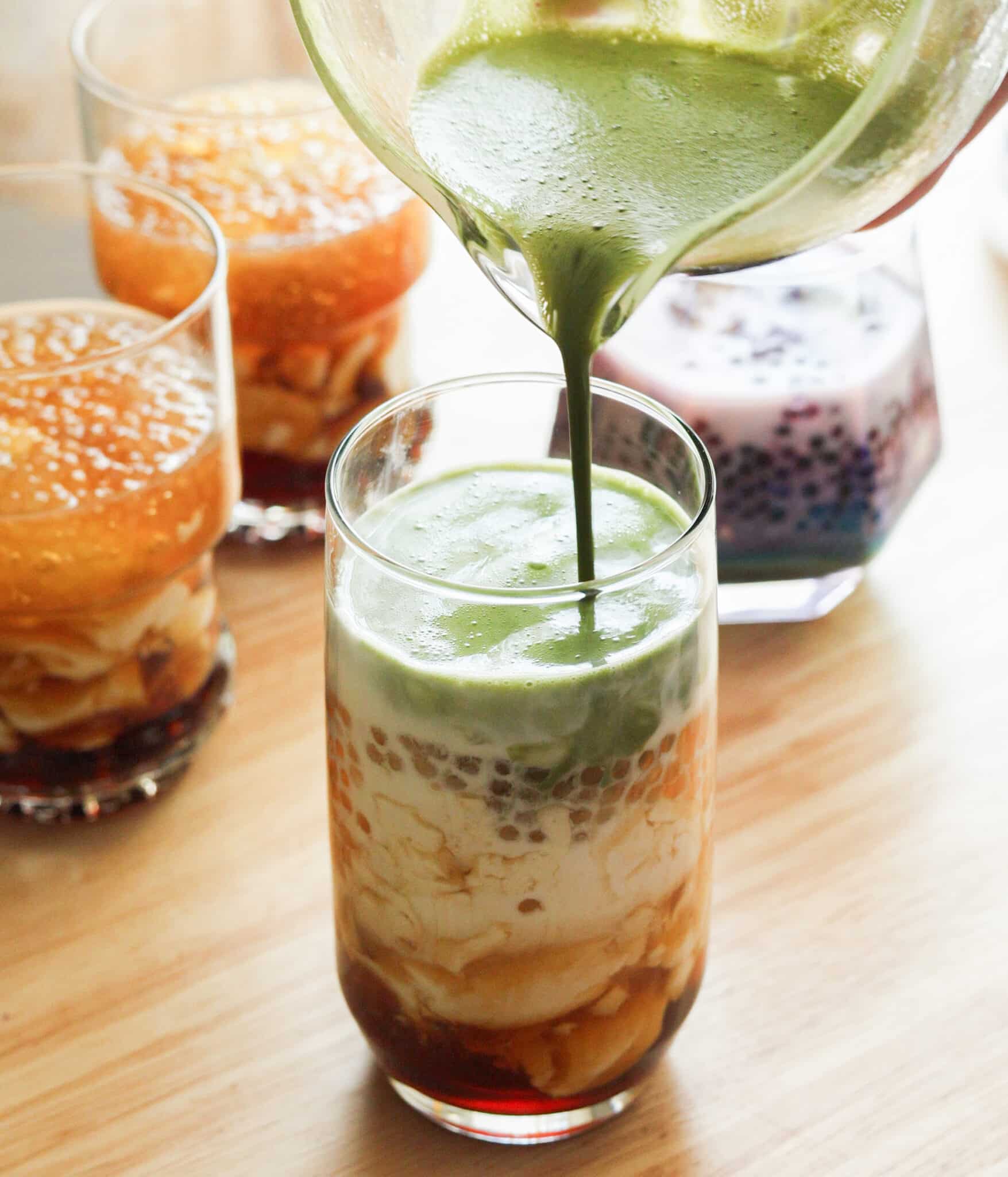 Pouring matcha mixture on top of taho.