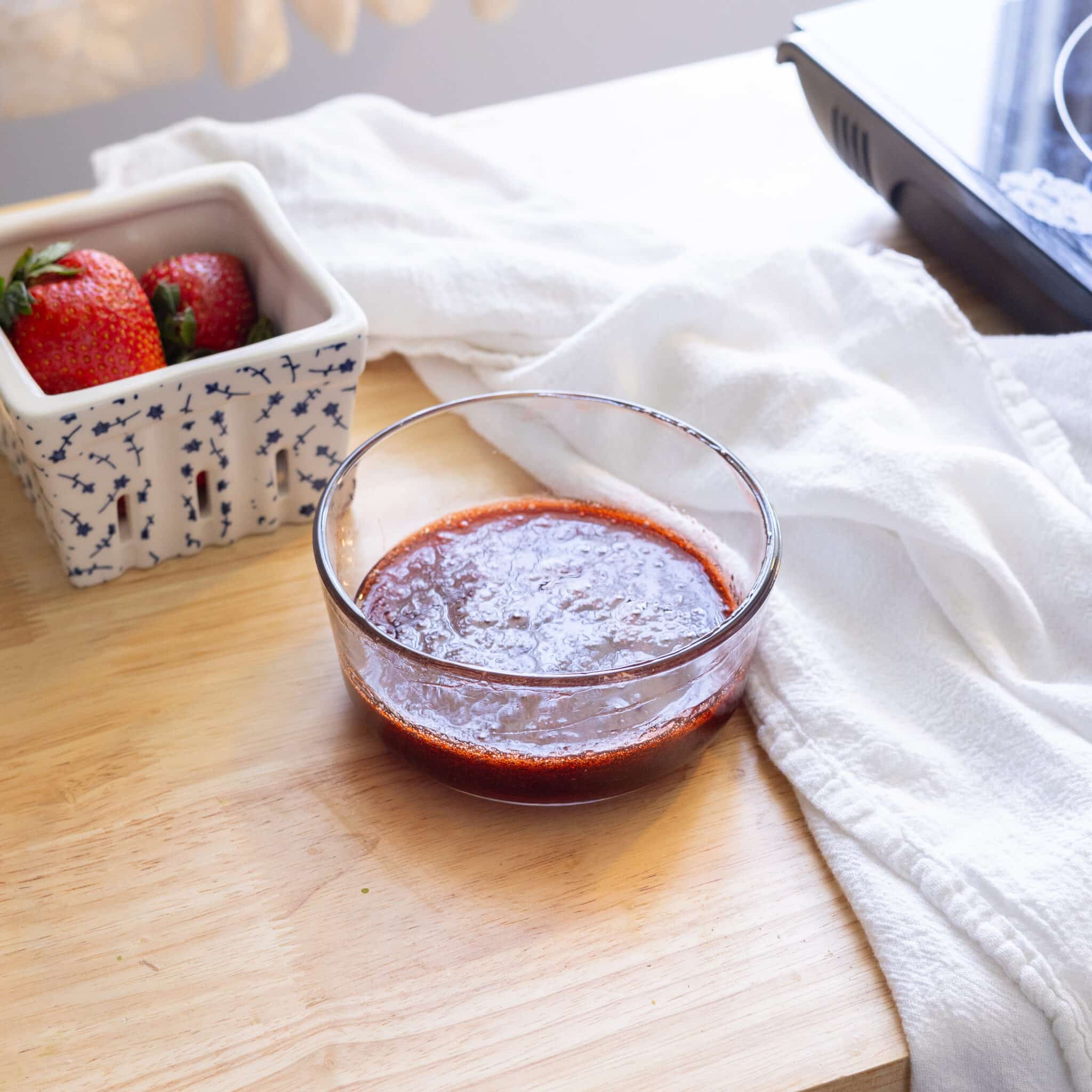 Homemade strawberry syrup in a glass container.