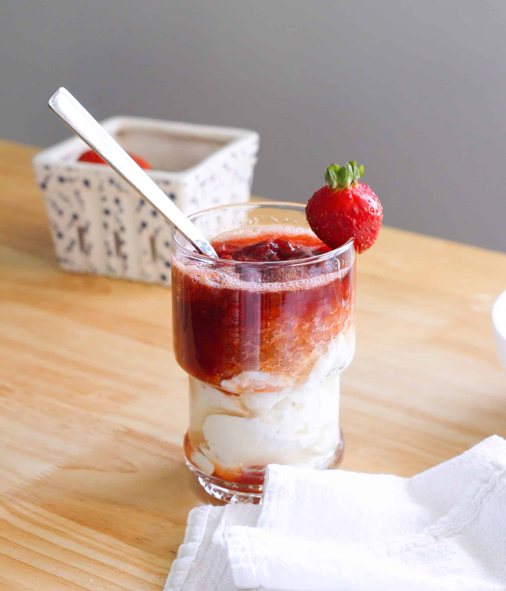 Strawberry taho in a glass cup with a spoon in it.