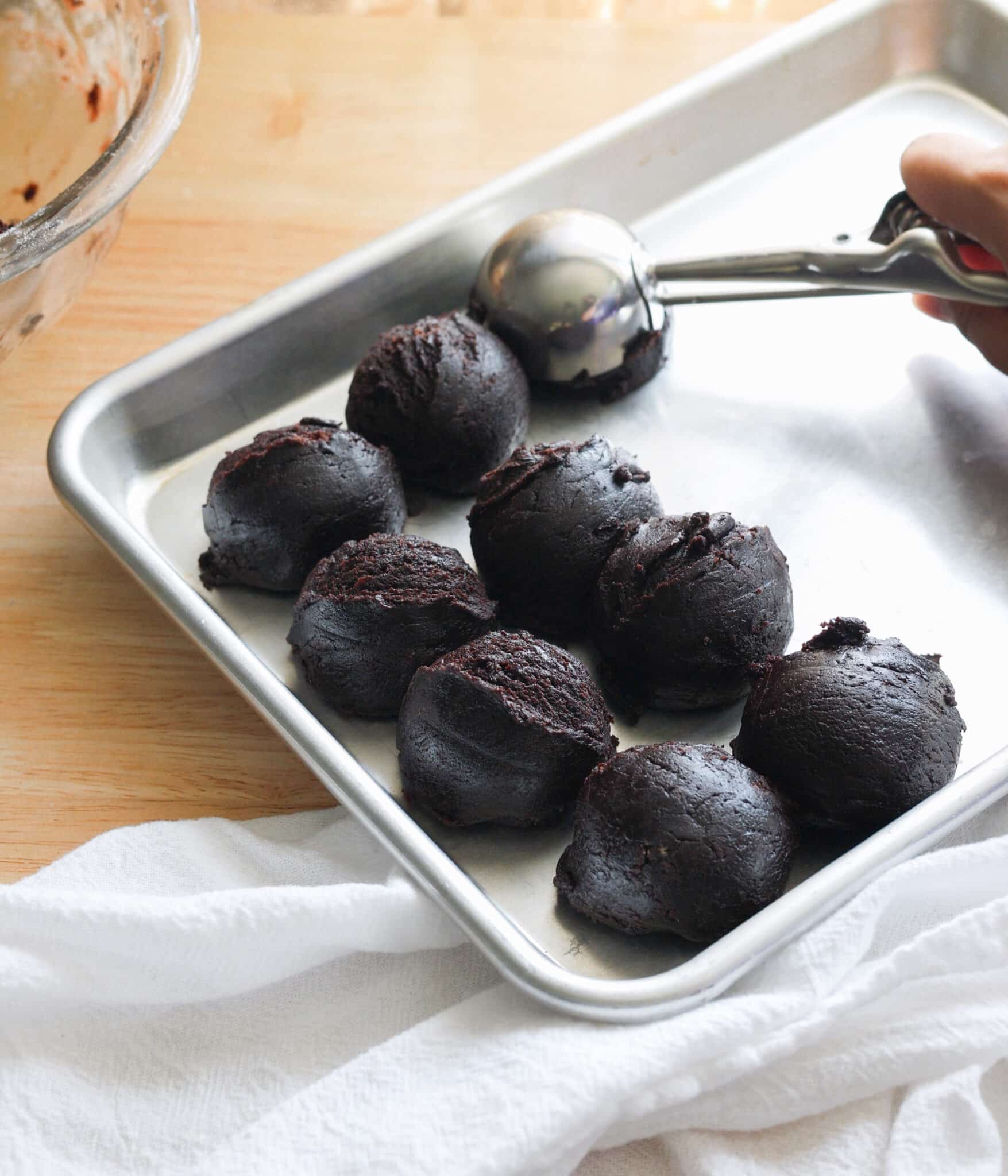 Scooped cookie dough balls resting on sheet tray.