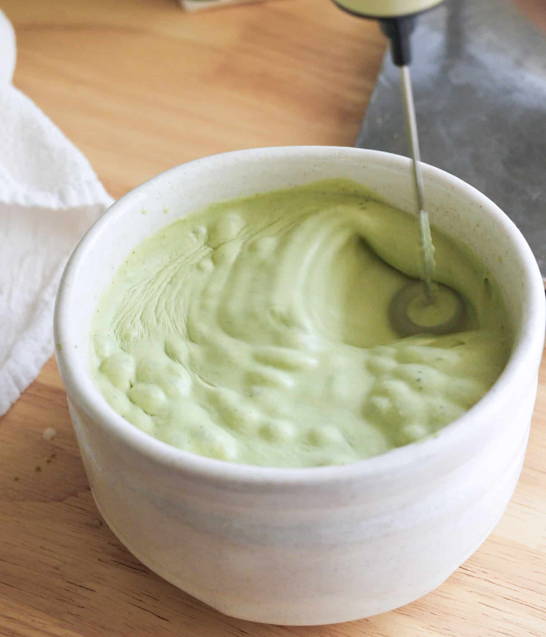 Frothing coconut milk matcha mixture in a bowl.