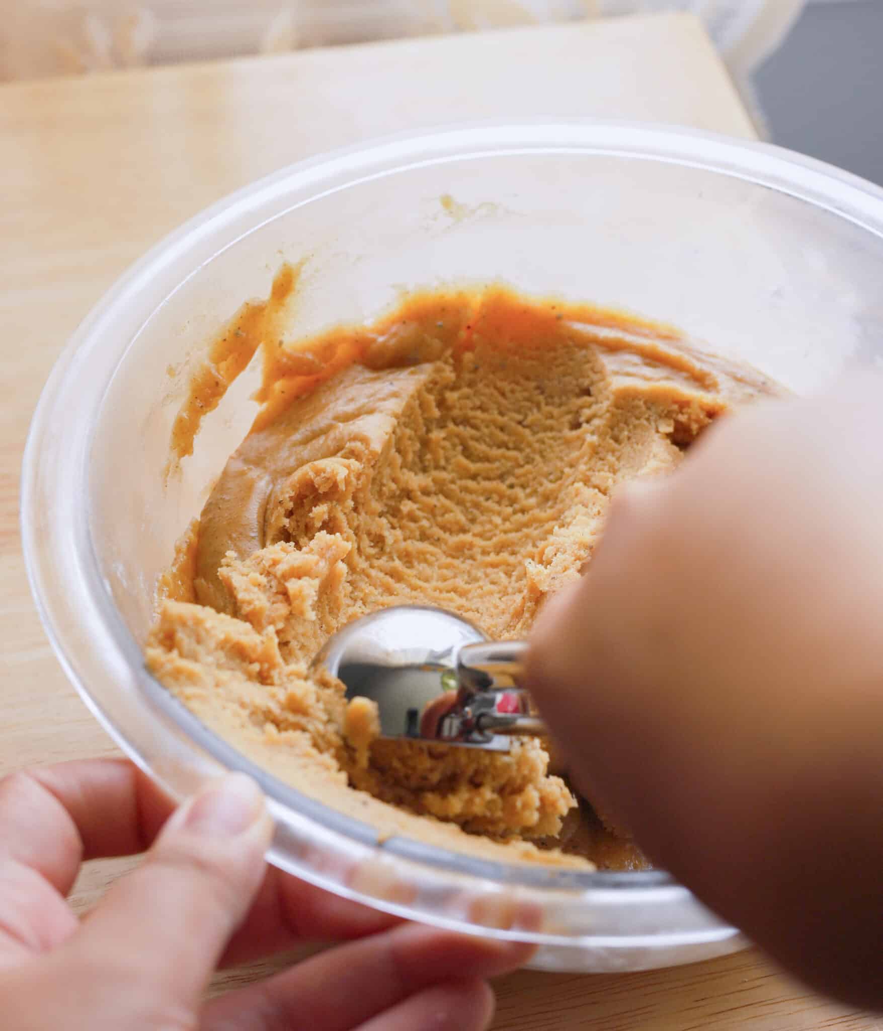 Scooping chilled chai sugar cookie dough with a cookie scoop.