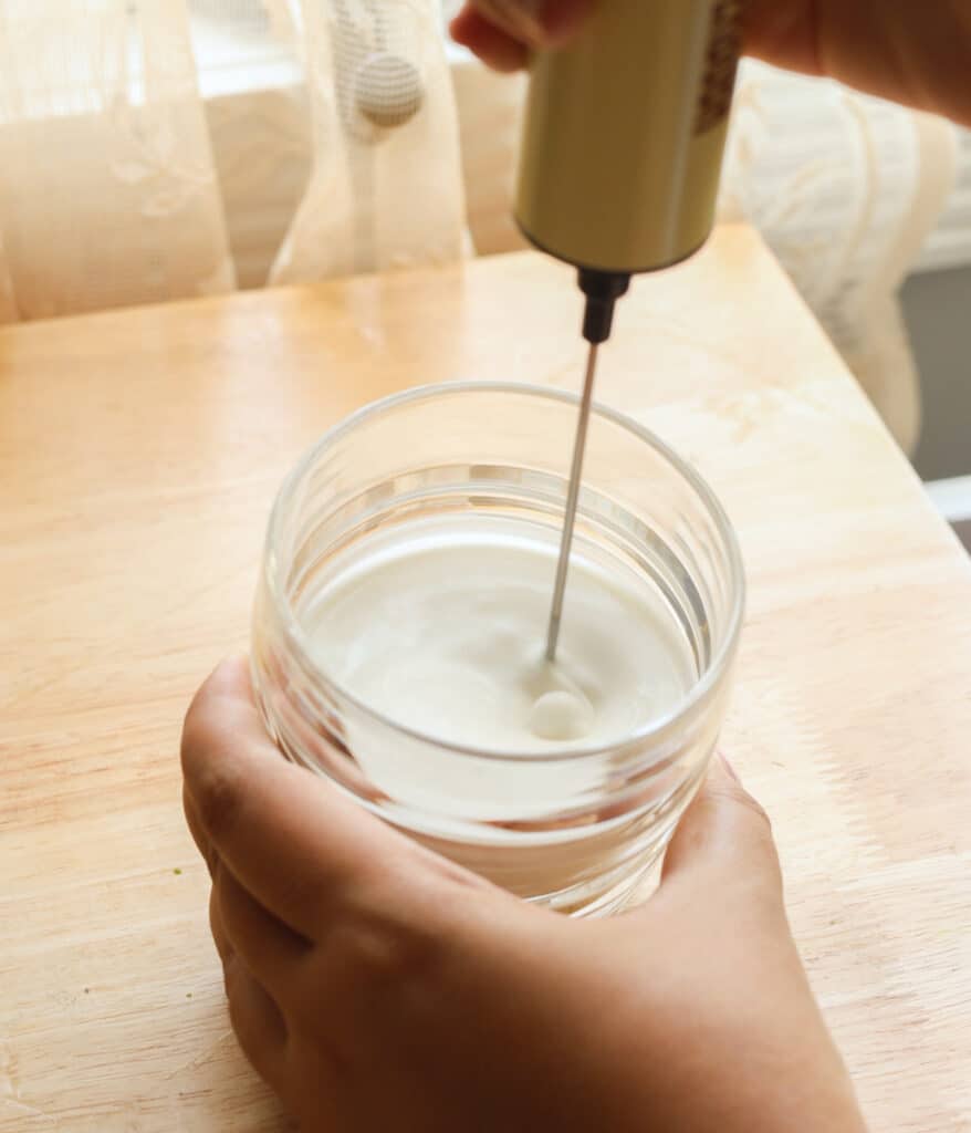 Using a frother to mix coconut cold foam ingredients.