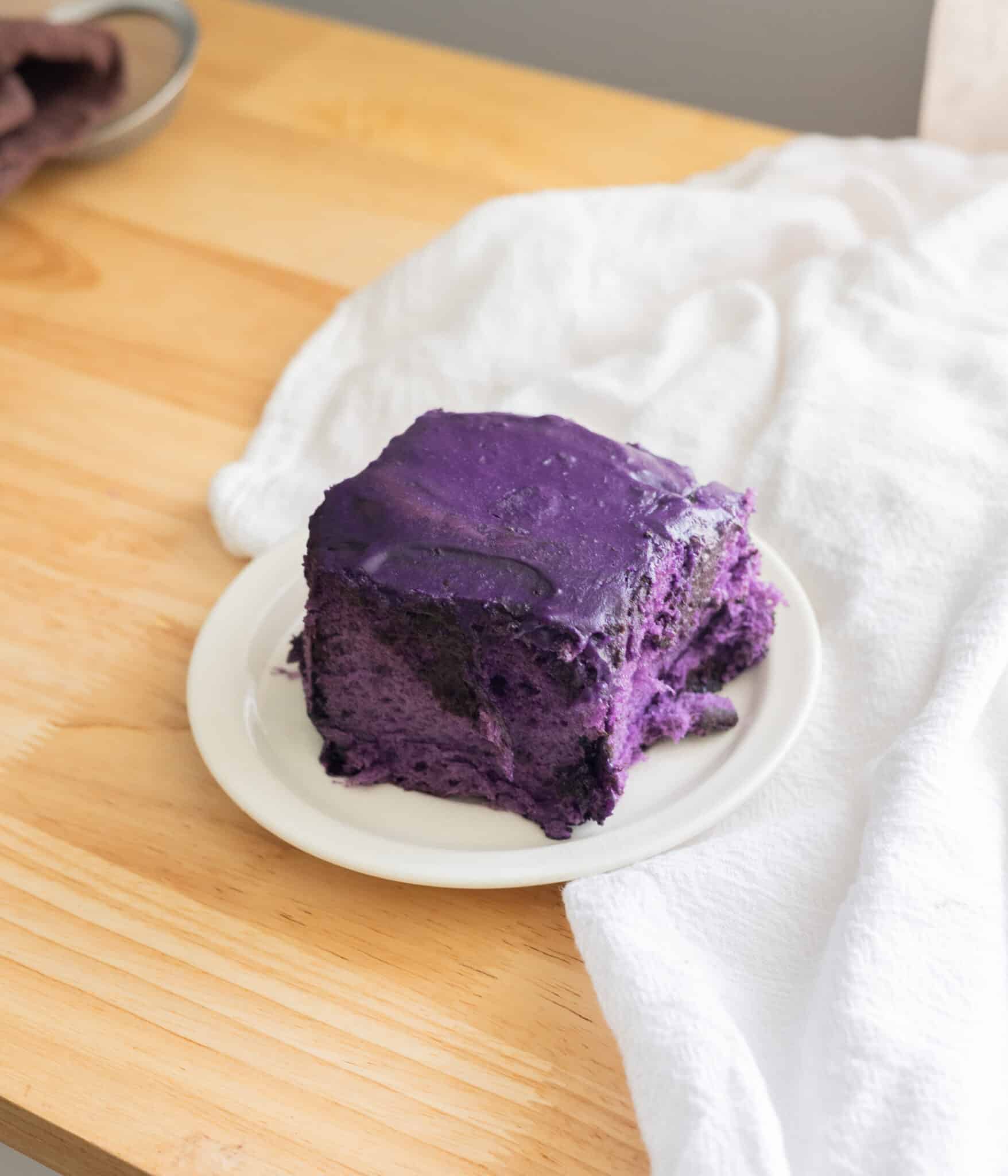 Purple ube cinnamon roll on a white plate.