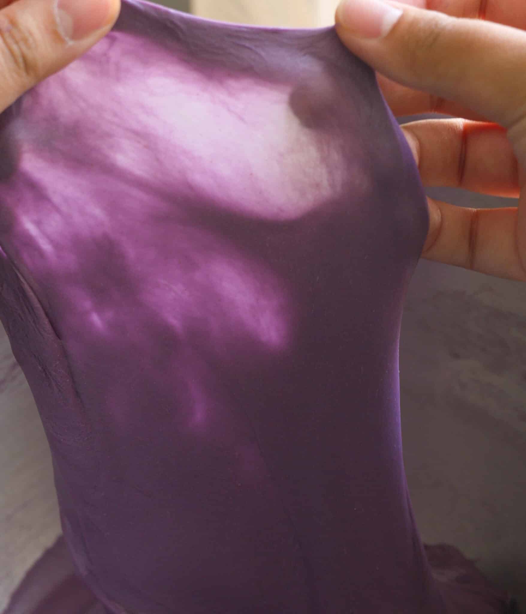 Ube brioche roll dough passing the windowpane test.