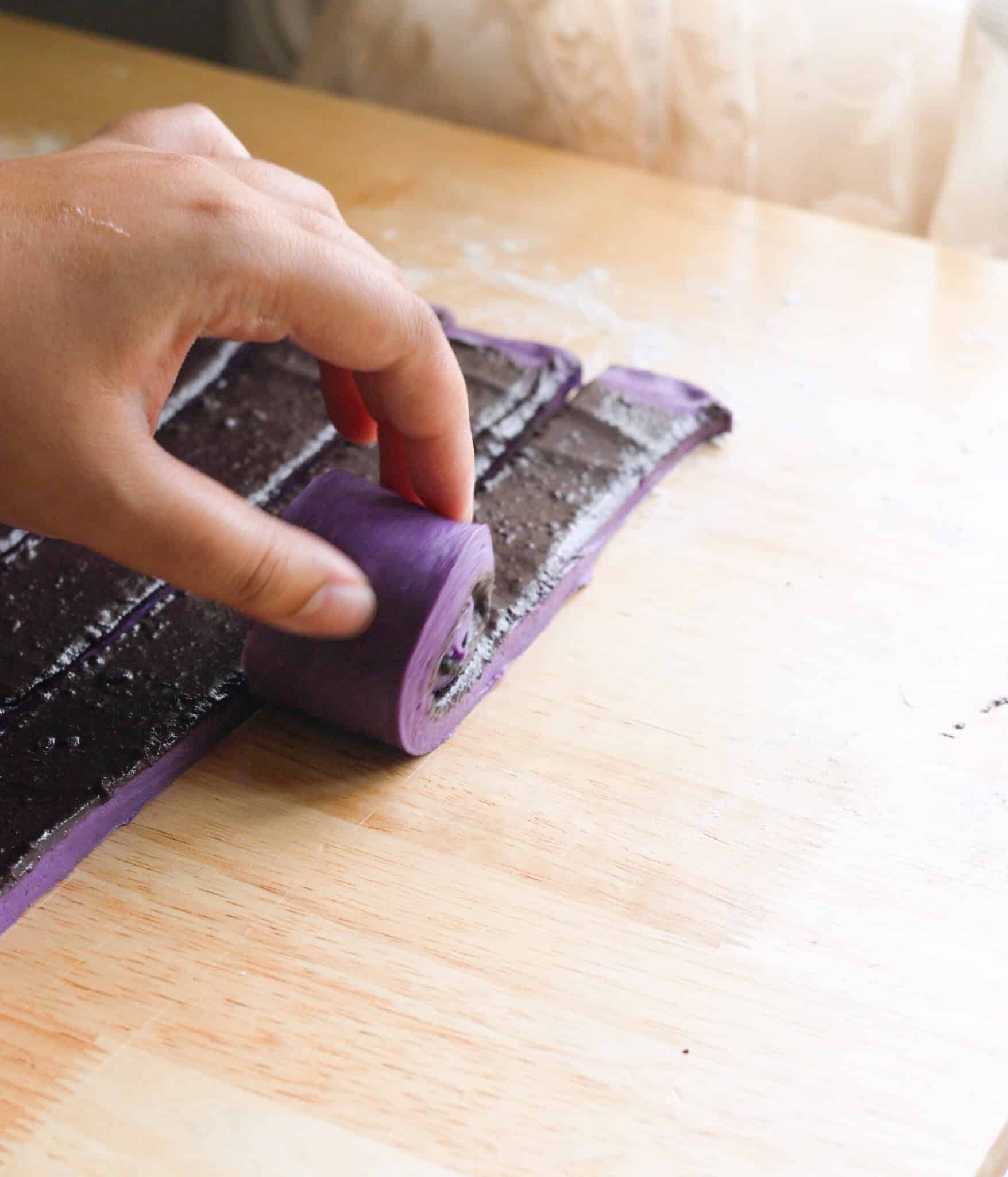 Rolling ube cinnamon dough strips.