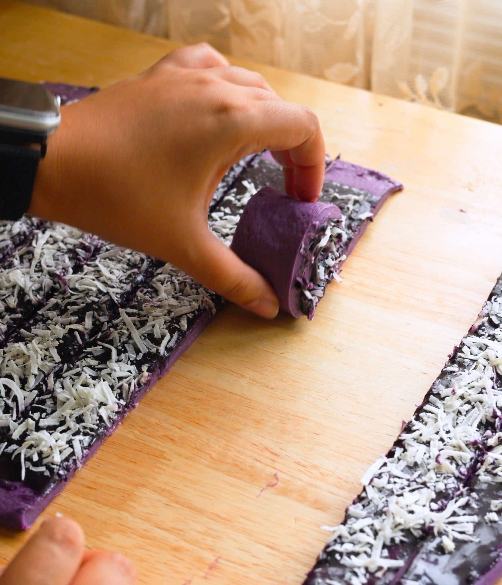 Rolling ube coconut dough strips.