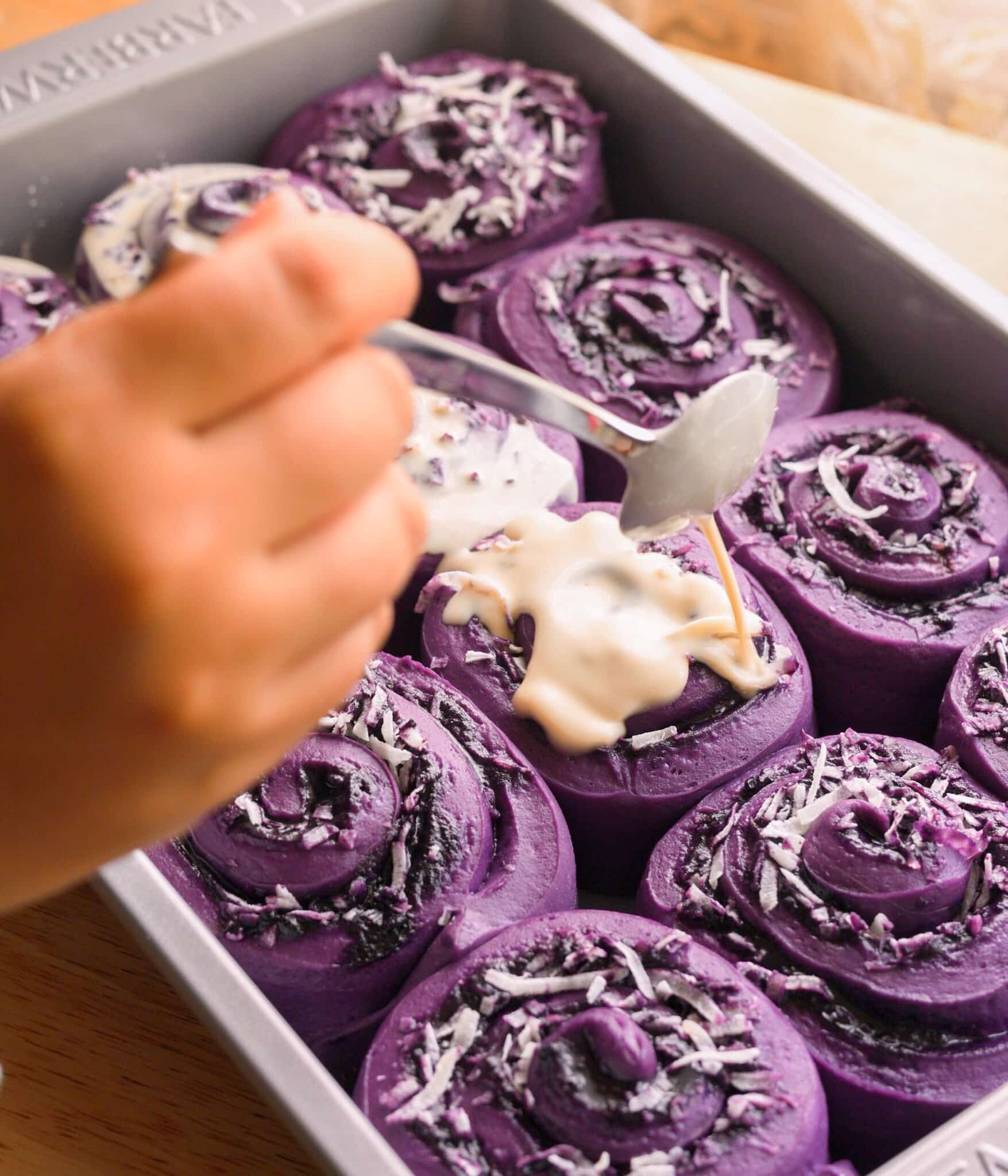 Topping ube coconut roll dough after second proof with coconut cream mixture.