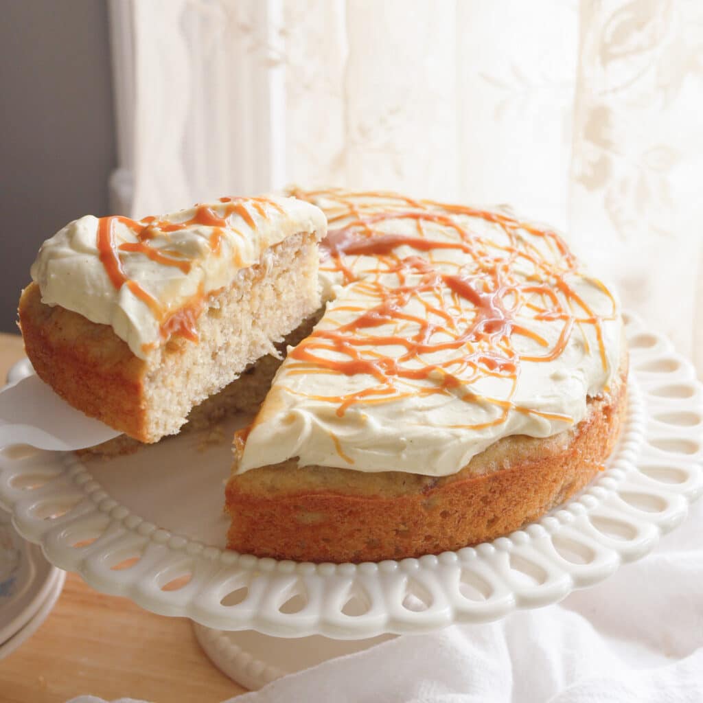 Taking slice of banana cake from cake stand.