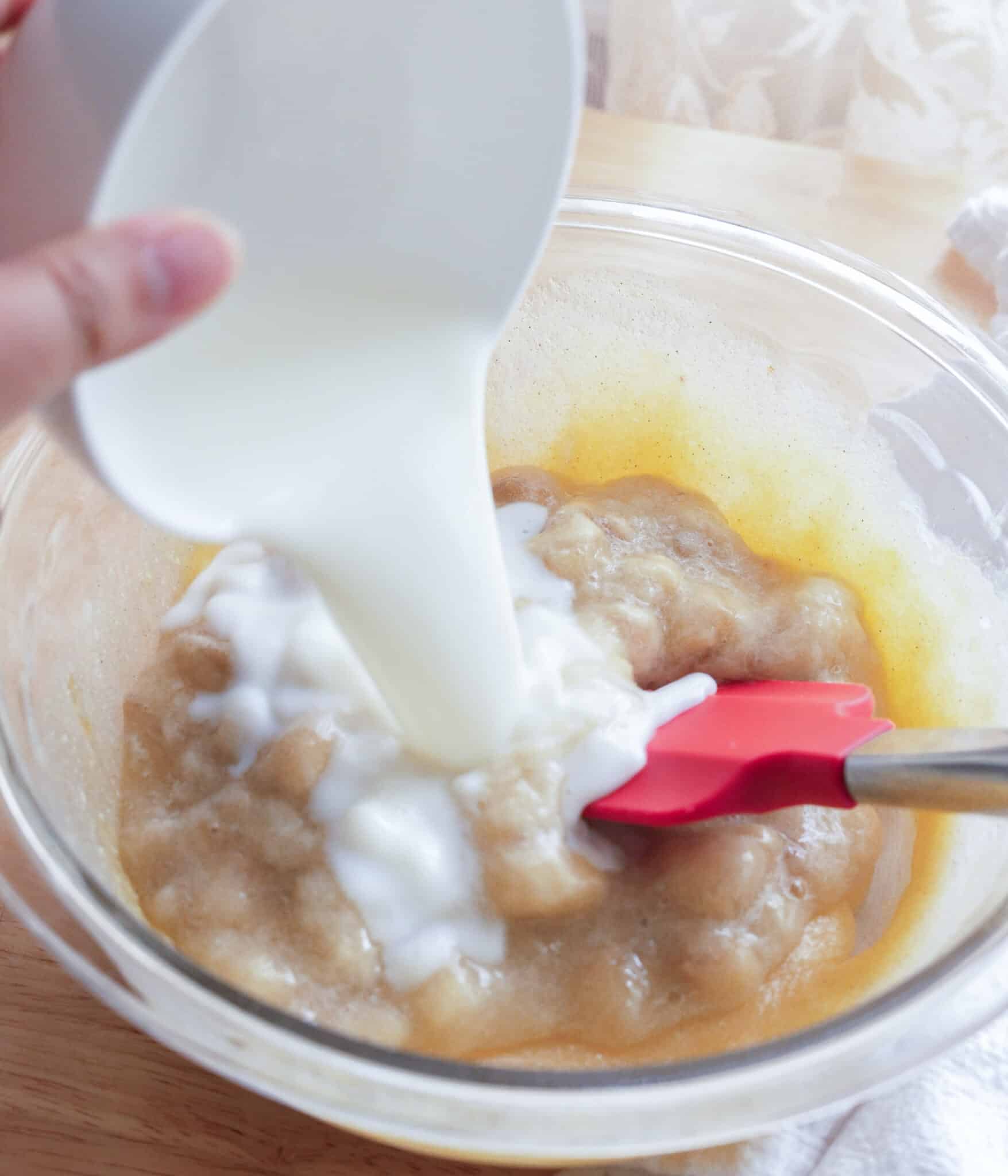 Pouring milk into wet ingredients for banana cake.