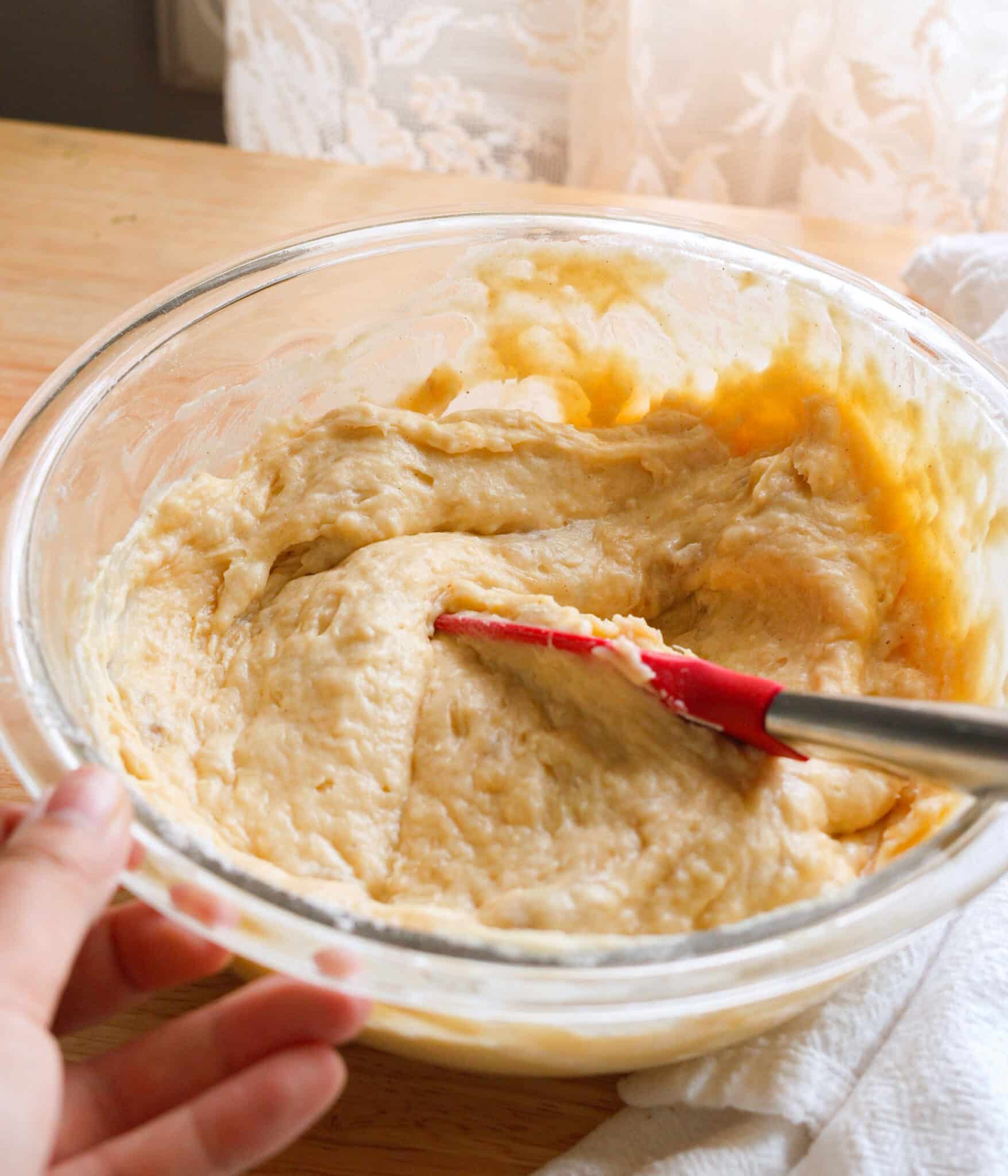 Banana cake batter in a glass mixing bowl.