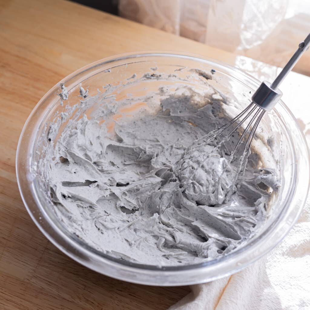 Black sesame cream cheese frosting in a glass mixing bowl.