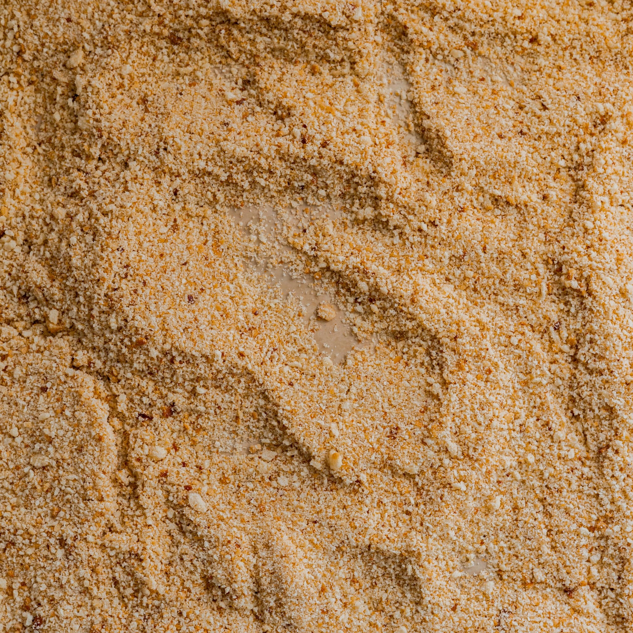 Toasted breadcrumbs spread out on a sheet pan.