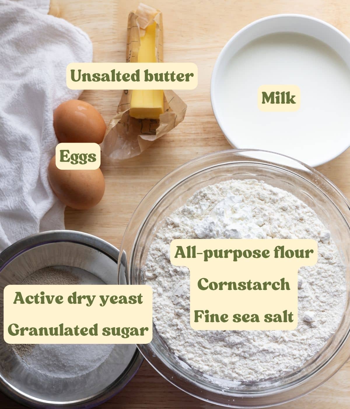 Labeled brioche roll dough ingredients laid out on a table.
