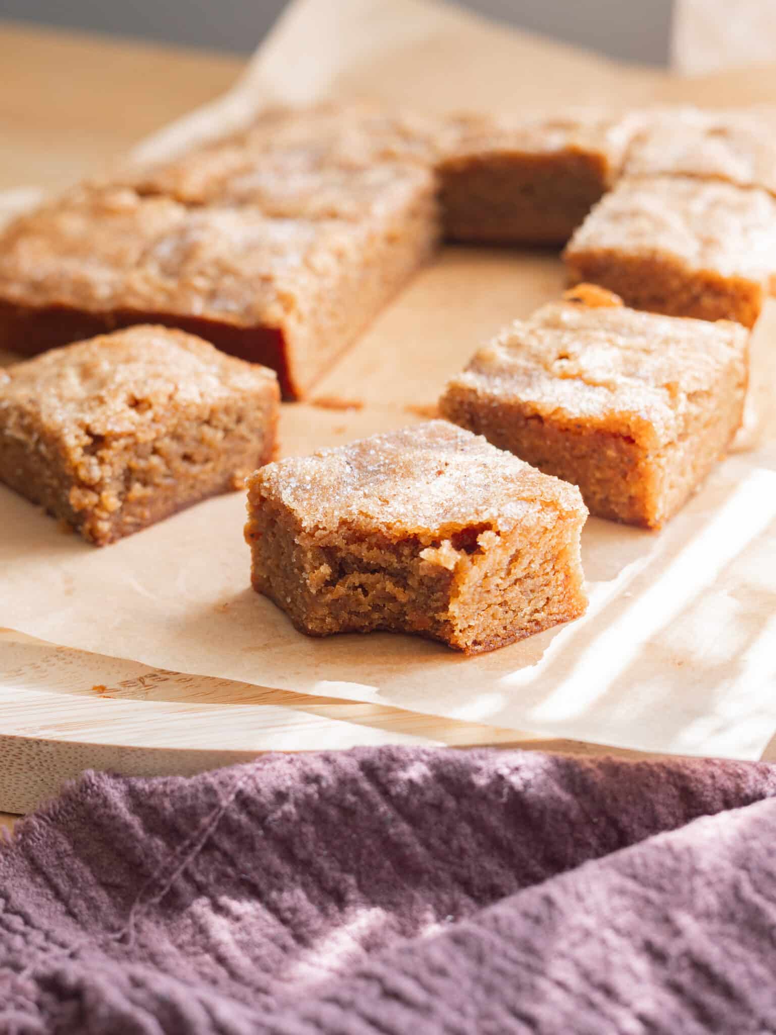 Chai blondie with a bite taken out of it on parchment paper.