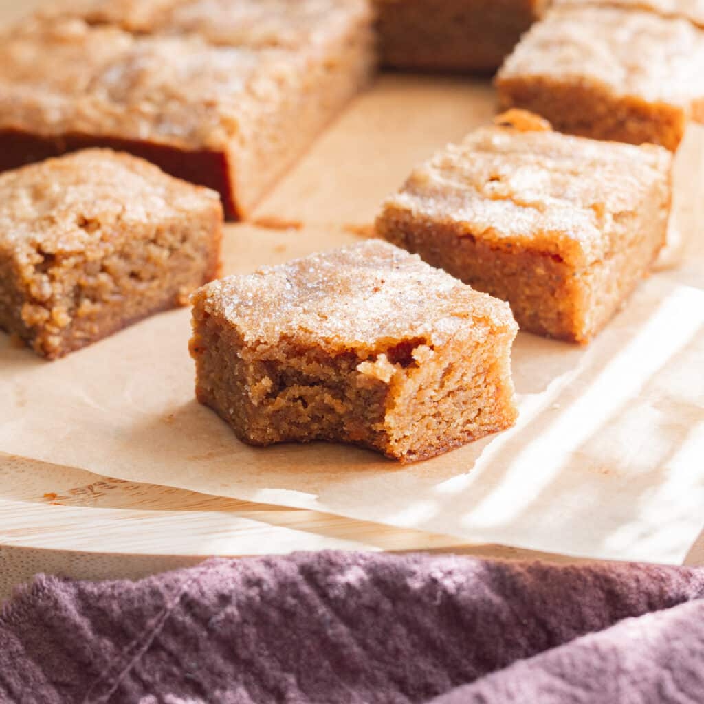 Chai blondie with a bite taken out of it on parchment paper.