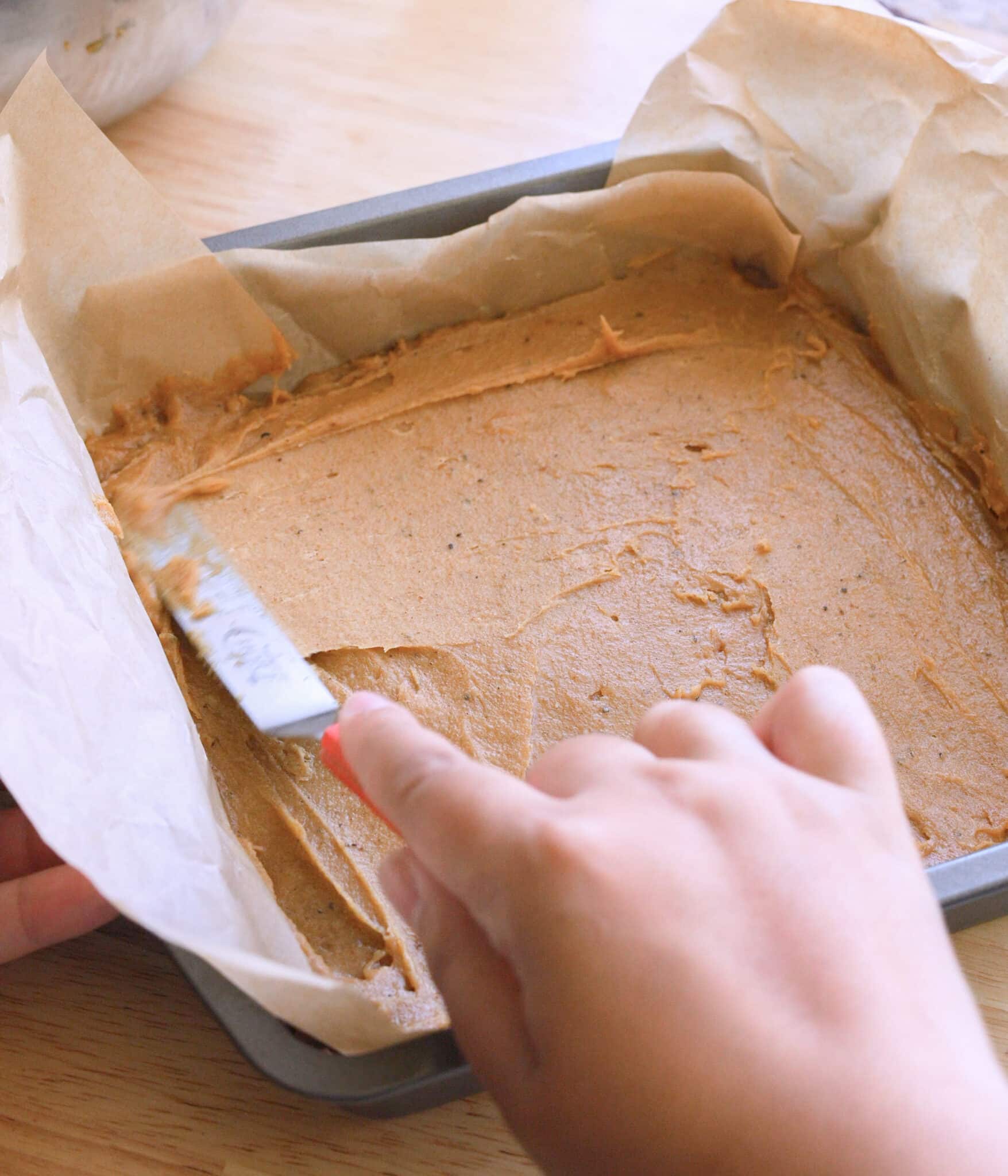 Spreading chai blondie batter into lined baking pan.