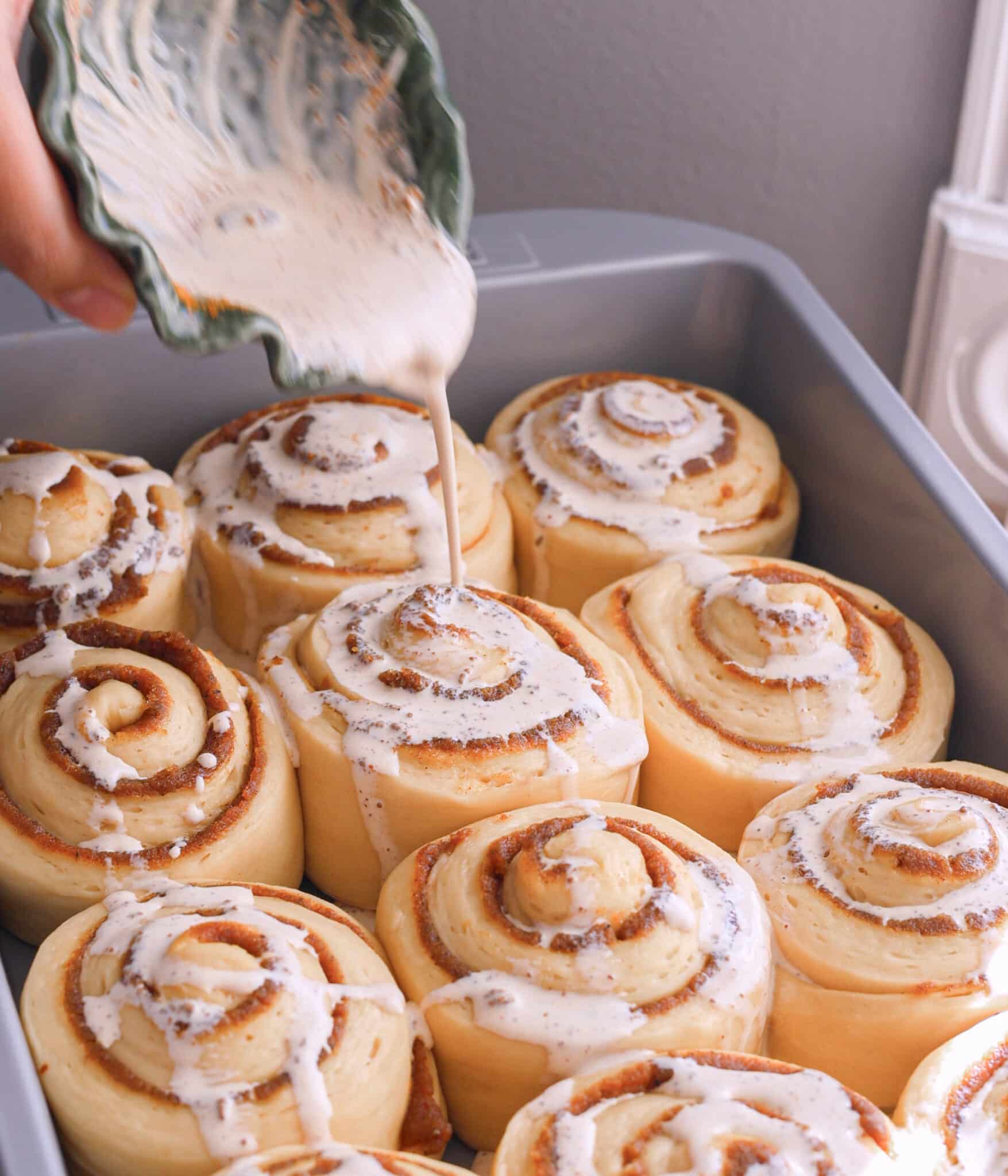 Pouring chai heavy cream on top of rolls.