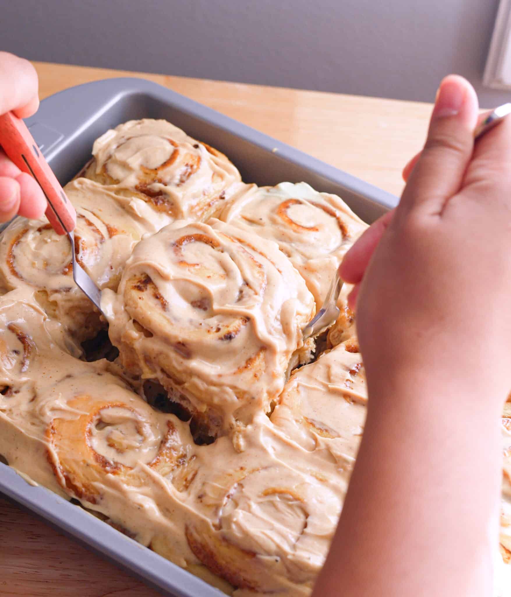 Taking chai frosted chai bun out of baking pan.