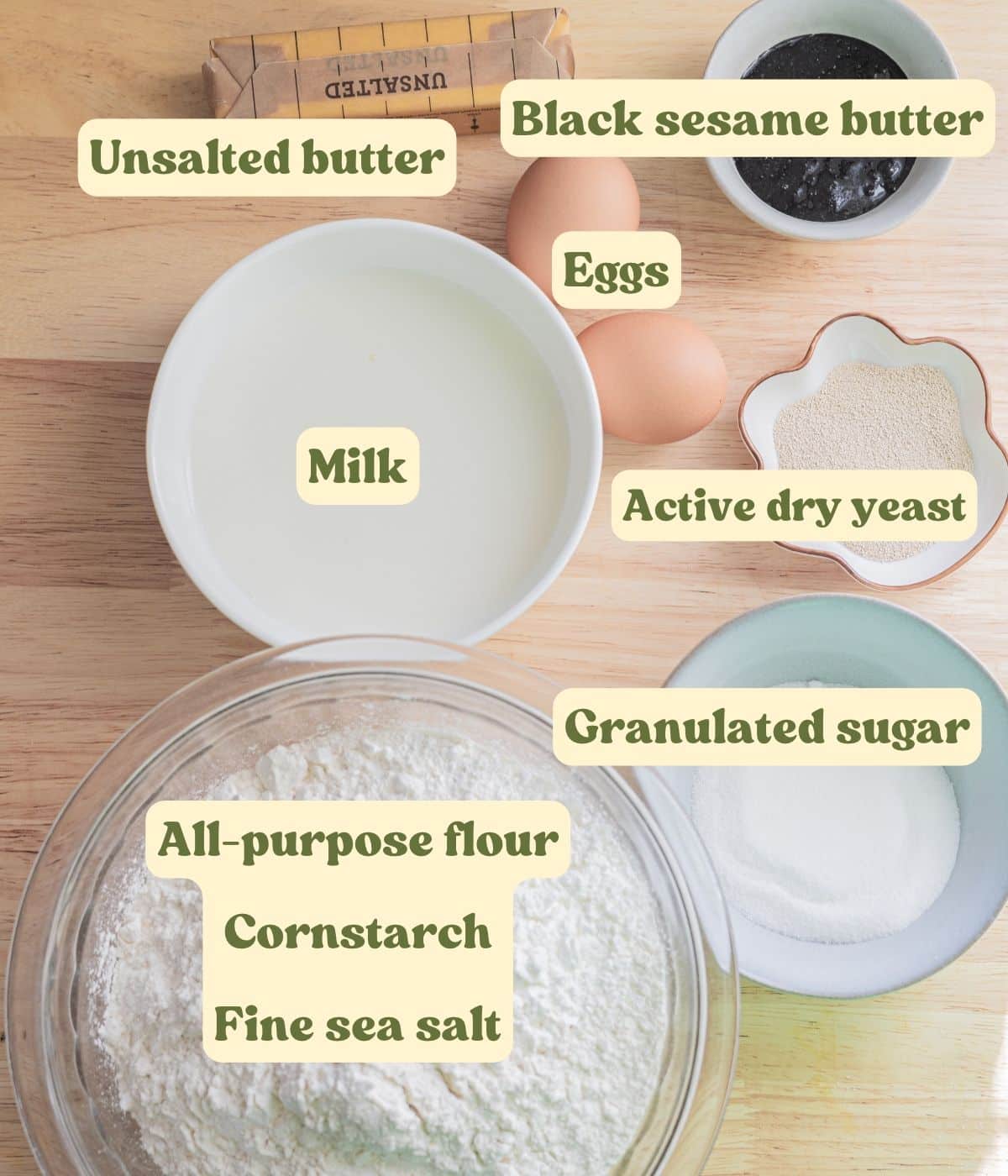 Labeled black sesame brioche roll dough ingredients laid out on a table.