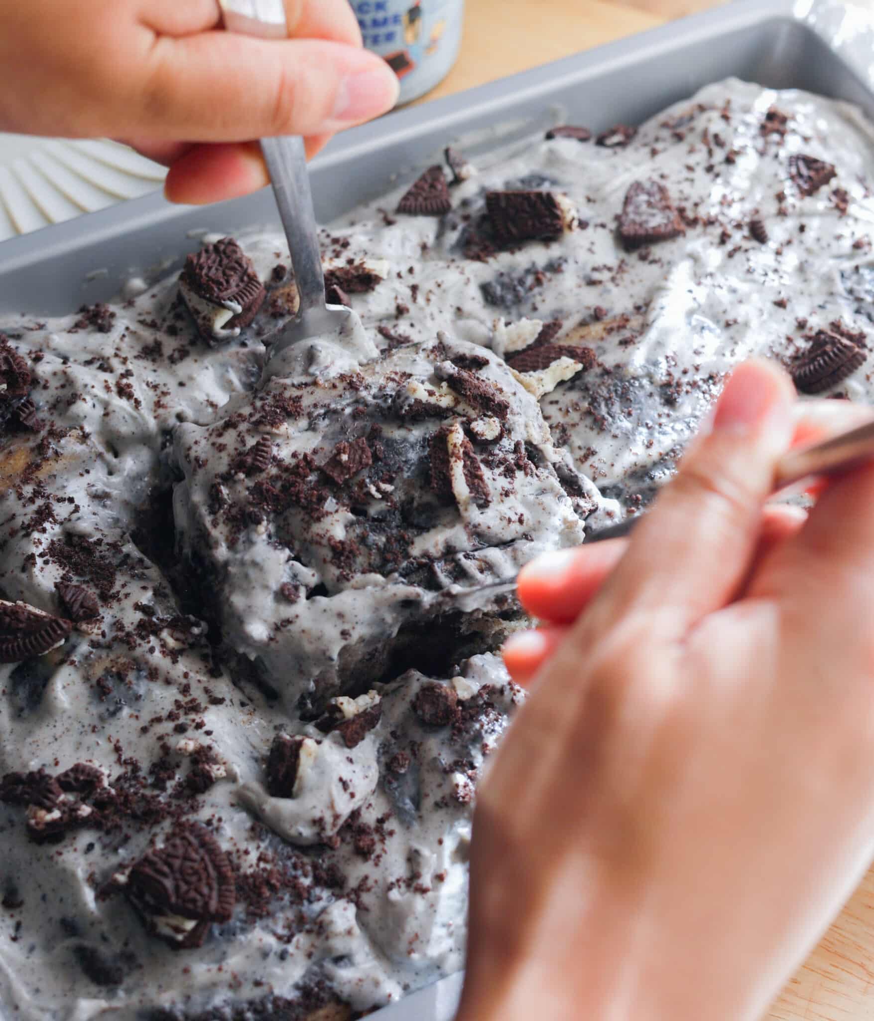 Taking frosted black sesame Oreo bun out of baking pan.