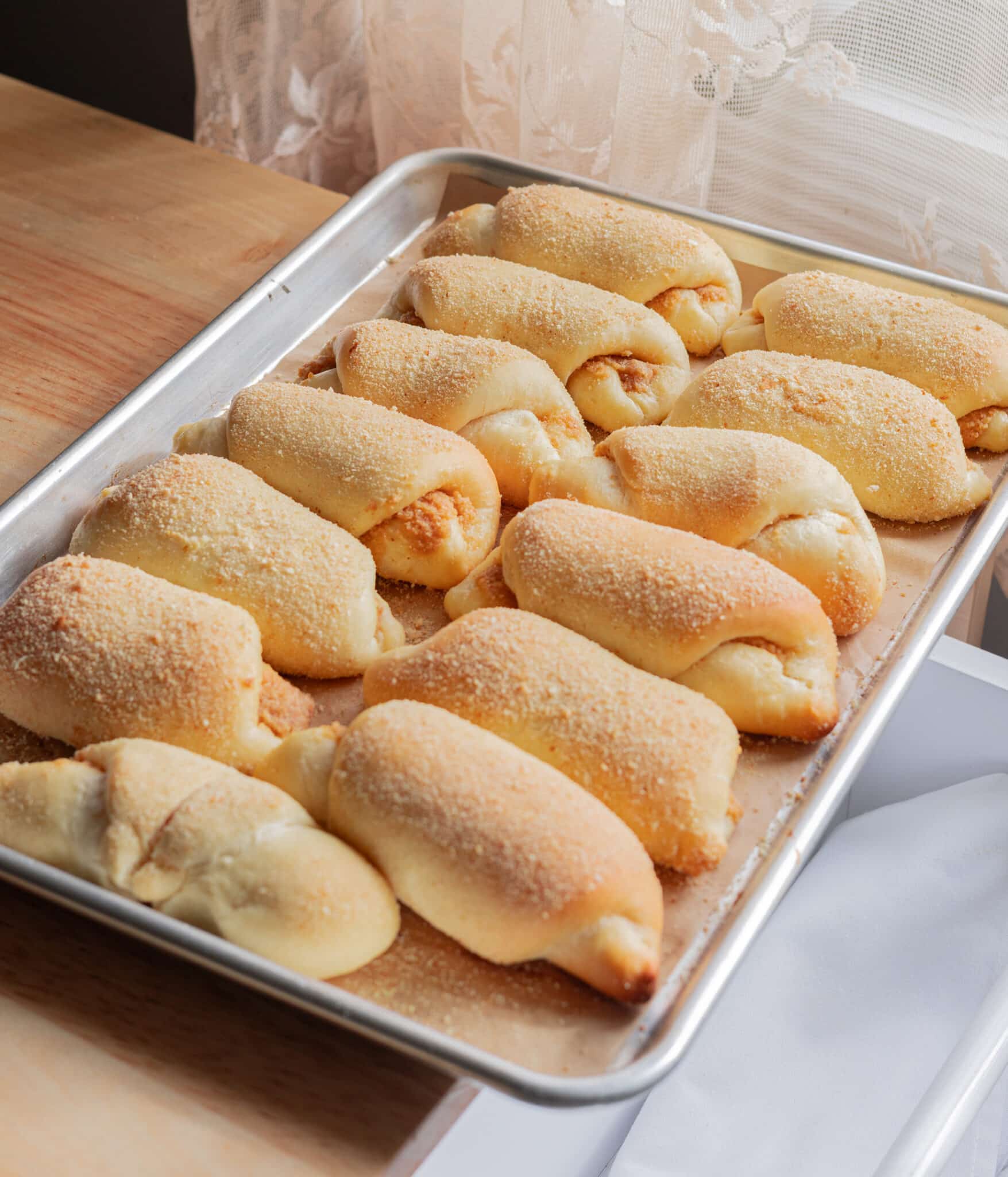 Freshly baked Spanish bread on a lined baking sheet.