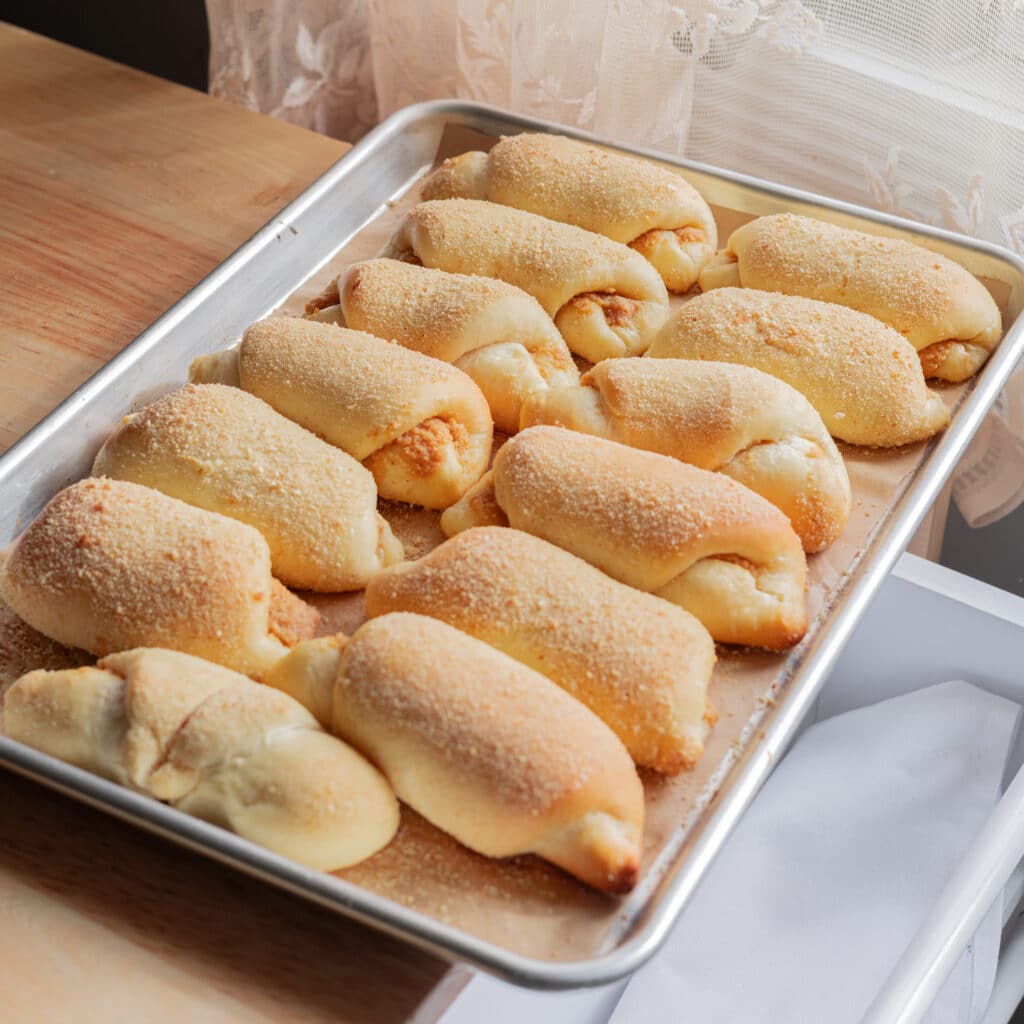 Freshly baked Spanish bread on a lined baking sheet.